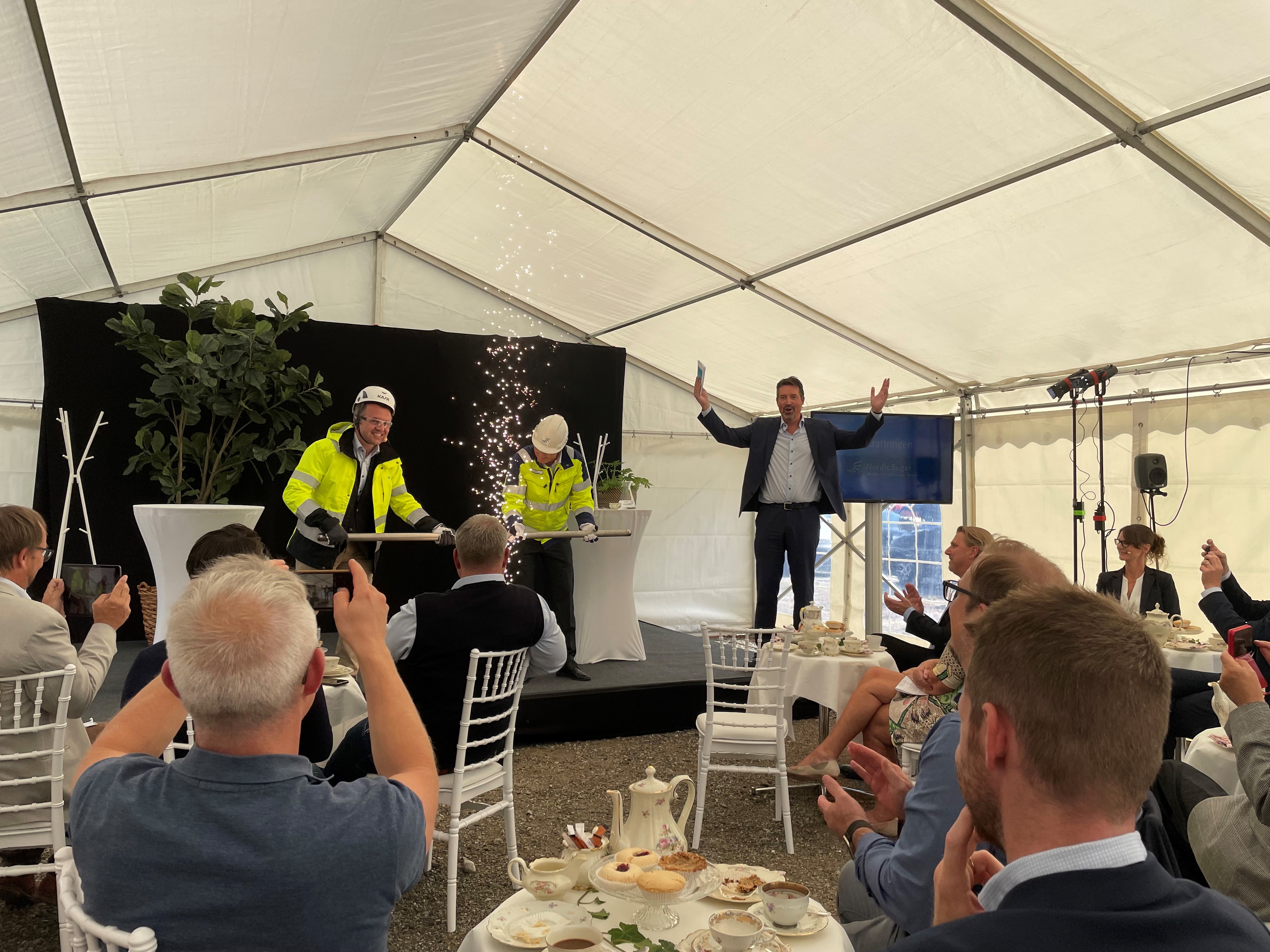 Olof Dahlgren fabrikschef f&ouml;r Nordic Sugar och Sezgin Kadir vd f&ouml;r Kraftringen kopplar samman f&ouml;rsta delen av den 1100 meter l&aring;nga r&ouml;rledning som ska leda fossilfritt producerad &aring;nga mellan Nordic Sugars sockerbruk och Kraftringens kraftv&auml;rmeverk i &Ouml;rtofta. Konferencier Johan Wester.